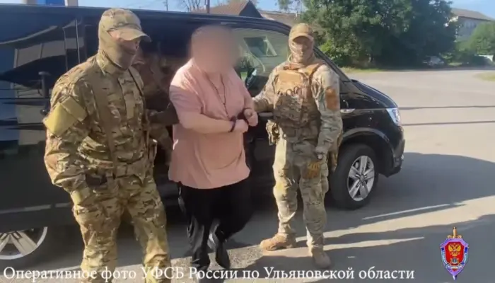 на фото Илья Журавлёв из Инзы в наручниках, его ведут два сотрудника ФСБ с закрытыми лицами.