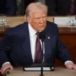 президент США Дональд Трамп выступает с трибуны с недовольным лицом
