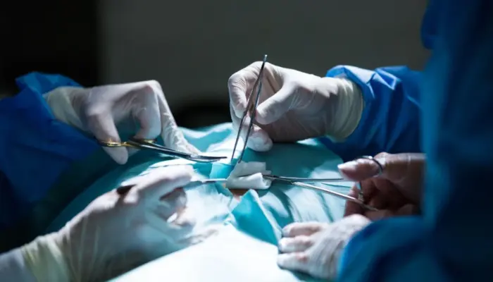 операционный стол, хирурги в медицинских перчатках и с инструментами проводят операцию