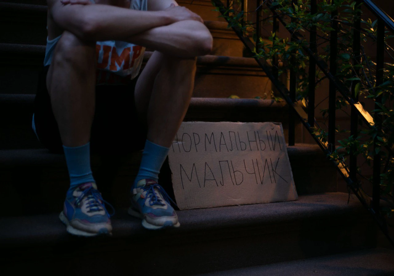 ноги мужчины и картонка с надписью "Нормальный мальчик"
