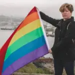 Дальневосточная ЛГБТ-активистка Регина Дзугкоева с прайд-флагом в руках на фоне порта