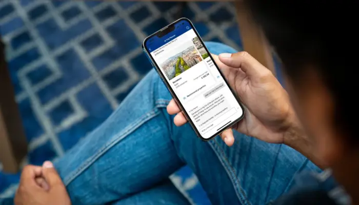 Человек держит в руках смартфон с открытым сайтом Booking.com