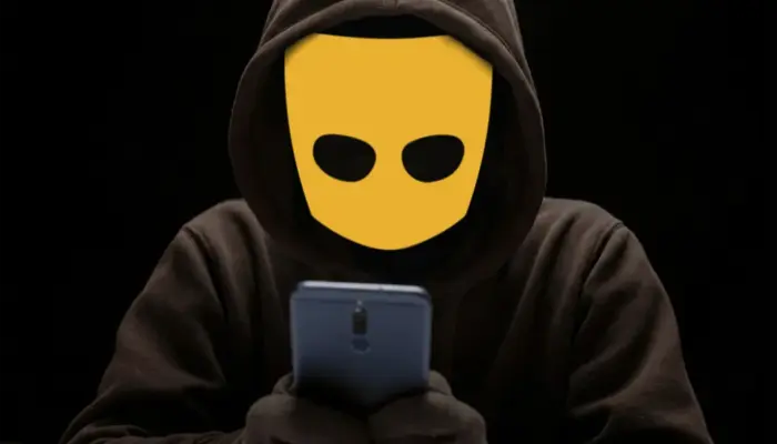 человек с логотипом Grindr вместо лица смотрит в телефон в темноте