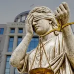 Статуя Фемиды делает фейспалм на фоне здания Московского городского суда