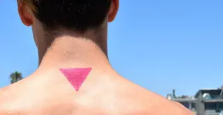 спина, шея и затылок мужчины с татуировкой в виде розового треугольника