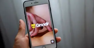 Телефон с открытым Grindr в руке