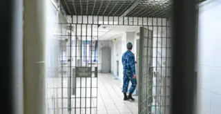 решётчатая дверь СИЗО и виден сотрудник Росгвардии