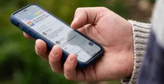 Телефон в руке мужчины, на экране знакомства ВКонтакте