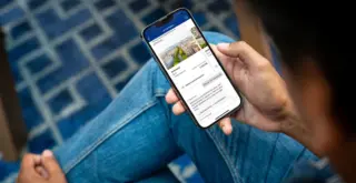 Человек держит в руках смартфон с открытым сайтом Booking.com