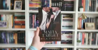 Книга Милы Финелли «Цель мафии» на английском на фоне книжной полки